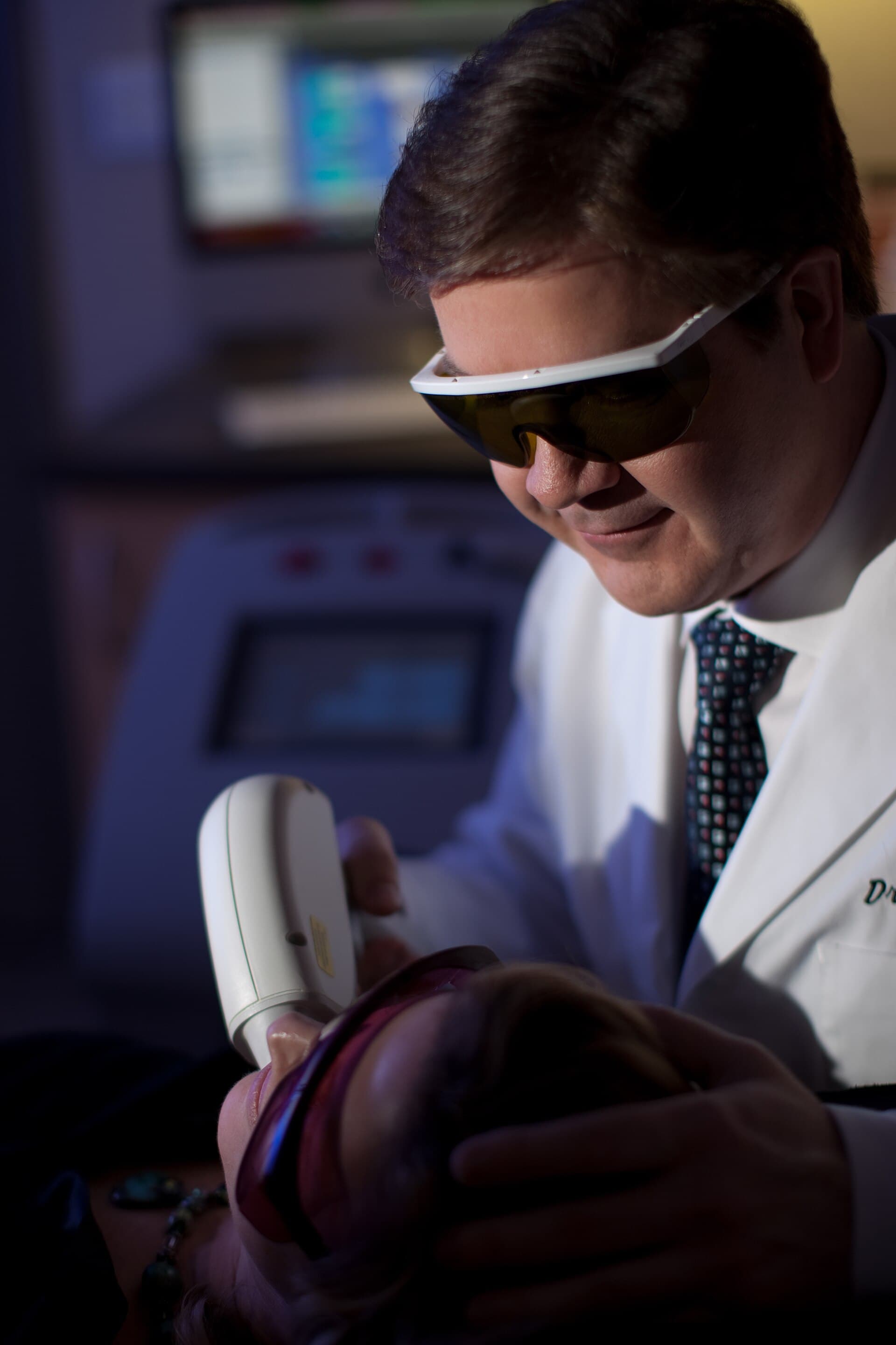Illustrative consultation scene with a clinician operating a Soprano laser hair-removal system; not a Luna client or a photo of Luna's clinic.